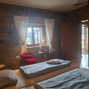 a bedroom with two beds and a red chair at 7 Roots - Leskovik in Leskovik