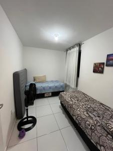 a small room with two beds and a television at Ap à 600 metros da praia, um verdadeiro paraíso! in Barra dos Coqueiros