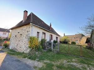 an old stone house with a fence in front of it at La Maison d'Amélie à Arnac-Pompadour in Arnac-Pompadour