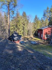 a house with a black roof next to a red barn at Huone 2-4 henkilölle Inkoossa in Inkoo
