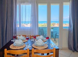 a dining table with glasses of wine and a view of the ocean at Casa Di Kontini in Acharavi