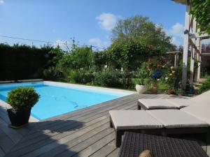 a swimming pool on a wooden deck next to a house at Les Arums de Fondeminjean in Vertheuil-en-Médoc