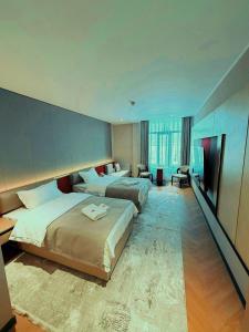 a hotel room with two beds and a television at AQMYRZA Inn in Zharkent