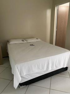 a white bed with white sheets and pillows on it at Pousada Medeiros in Cedro