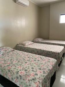 three beds in a room with flowers on them at Pousada Medeiros in Cedro