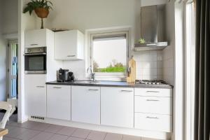 a white kitchen with a sink and a window at Rekerlande 274 in Warmenhuizen