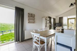 a kitchen with a wooden table and white chairs at Rekerlande 274 in Warmenhuizen