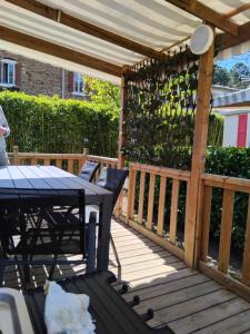 a wooden deck with a pergola and a table and chairs at Mobil home LE COUCOU in Le Martinet