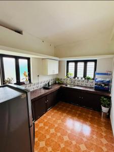 a large kitchen with a counter and some windows at Jimmy nivas in Kottayam
