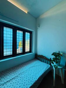 a bedroom with a bed and two windows at Jimmy nivas in Kottayam