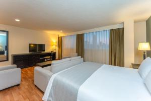 a hotel room with a white bed and a television at Hotel Dann Av. 19 in Bogotá