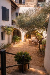 a courtyard of a house with a tree and chairs at La Cachette in Aigues-Vives