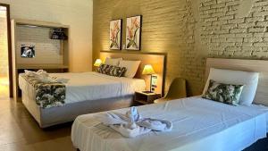 two beds in a hotel room with towels on them at Vale das Orquídeas Pousada in Socorro