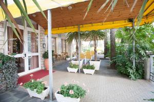 a patio with potted plants and a yellow canopy at Hotel Milena in Cervia
