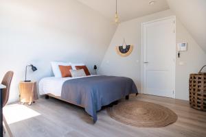 a white bedroom with a bed and a wooden floor at Yn 'e Haven Logies in Earnewâld