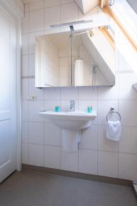a white bathroom with a sink and a mirror at Yn 'e Haven Logies in Earnewâld +14 photos