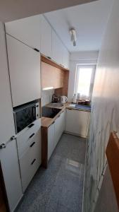 a small kitchen with white cabinets and a window at U Stosela- wiejski dom w górach in Biały Dunajec
