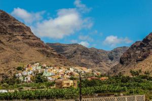 a village on a hill with mountains in the background at Hotel Gran Rey in Valle Gran Rey