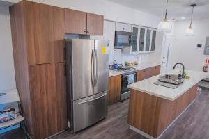 a kitchen with a stainless steel refrigerator and wooden cabinets at Executive 1BR Downtown POS with ensuite bath in Port-of-Spain
