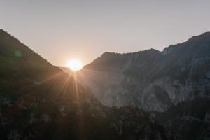 a sun setting over a mountain range with the sun setting at Hotel Porto Tara in Žabljak