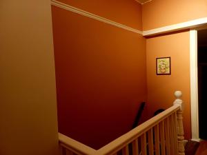 a hallway with orange walls and a staircase at Entire flat with 2 separate rooms in Norwood
