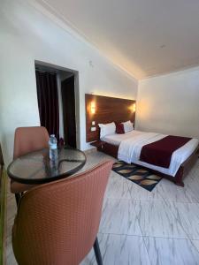a hotel room with a bed and a table and chairs at Vine Gardens & Hotel, Mityana in Mityana