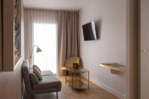 a living room with a chair and a table and a window at Hôtel le XIX in Béziers