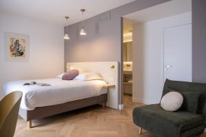 a bedroom with a bed and a chair and a mirror at Hôtel le XIX in Béziers
