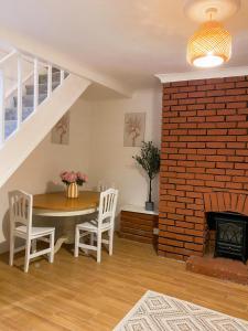 a dining room with a table and a brick fireplace at Cozy en suite room in King's Lynn