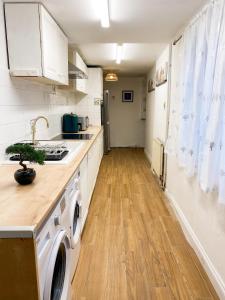 a kitchen with white cabinets and a washer and dryer at Cozy en suite room in King's Lynn