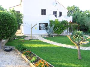 a garden in front of a white house at Apartmani Dolencic in Krk