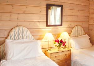 two beds in a room with wooden walls at Curlew Lodge in Dumfries