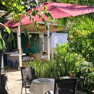 a patio with two tables and a pink umbrella at Hotel suites Las Abuelas in Copán Ruinas