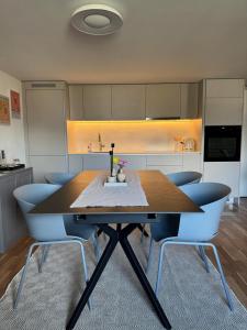 a kitchen with a wooden table and blue chairs at Chez Leny in Monthey