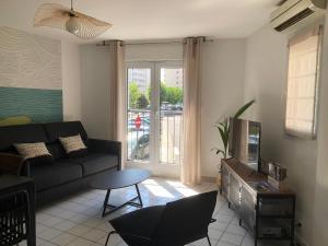 a living room with a black couch and a tv at Maison de ville proche mer in Les Sables-d'Olonne