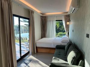 a room with a couch and a bed and a window at SafeHouse resort เซฟเฮ้าท์รีสอร์ท in Ban Laem Phai