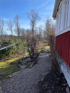 a gravel path next to a red building with a fence at Guesthouse Holmen in Färgelanda