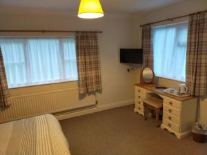 a bedroom with a desk and a bed and windows at The Green Dragon Inn in Redditch