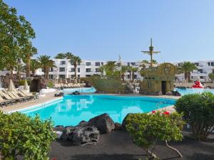 a large swimming pool in a resort with chairs at H10 Suites Lanzarote Gardens in Costa Teguise