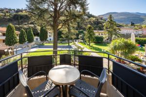 a balcony with a table and chairs looking out at a park at Ventus Park Hotel in Nago-Torbole