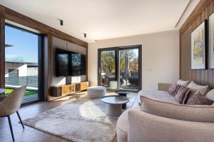 a living room with a couch and a tv at Villa Porta Verde IV - Infinity pool BBQ Luxury in Balatonalmádi