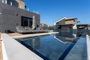 a swimming pool with chairs and a house at Villa Porta Verde IV - Infinity pool BBQ Luxury in Balatonalmádi
