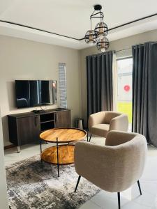 a living room with a table and chairs and a tv at Xitshavani Lodge in Phalaborwa