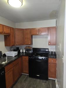 a kitchen with a black stove and wooden cabinets at Convenient Downtown Apartment in Saint Louis
