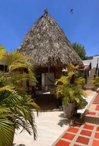 a resort with a straw hut with chairs and palm trees at Hotel Ocean Taganga Internacional in Taganga
