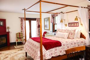 a bedroom with a canopy bed and a desk at Stonecroft Inn in Ledyard Center