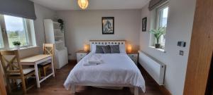 a bedroom with a bed and a desk and a chair at Three Hares Farmhouse, Galway in Craughwell