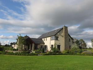 a large white house with a green lawn at Three Hares Farmhouse, Galway in Craughwell
