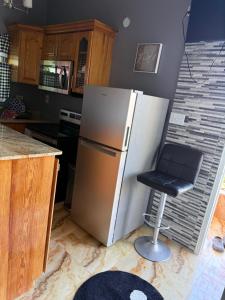 a kitchen with a stainless steel refrigerator and a stool at Montego Bay, Ironshore Luxury Studio in Montego Bay