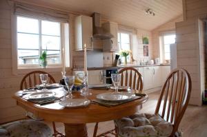 a kitchen with a wooden table with chairs and a dining room at Lapwing Lodge in Dumfries